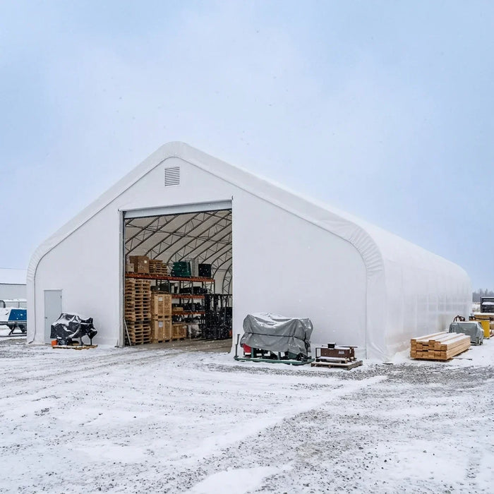Snowy outdoor site with stored pallets visible, Snow Series™ 40' x 80' Dual Truss Storage Shelter