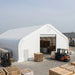 Snow Series™ 40' x 60' Dual Truss Storage Shelter at busy warehouse yard with forklifts
