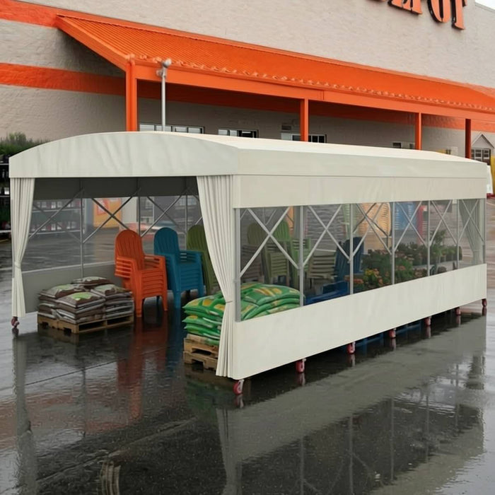 Retractable mobile shelter with white cover and clear side panels sheltering pallets of bagged goods and stacked chairs
