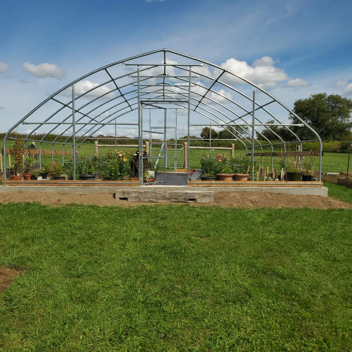 Customer photo: galvanized steel tunnel greenhouse frame with door, front view, before the poly cover is installed
