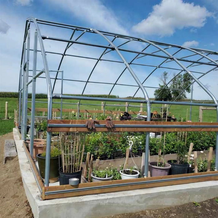 Customer photo: close-up of tunnel greenhouse steel frame and wood base rails with potted plants inside