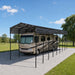 Metal shed shelter outdoors covering a Class-A RV on concrete.